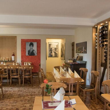 Innenaufnahme Gastraum Ristorante Esposito mit Esstischen und rustikalem Weinregal