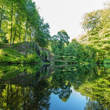 Landschaftsaufnahme mit Luisenthaler Wasserfall und Teich im Schlosspark Altenstein