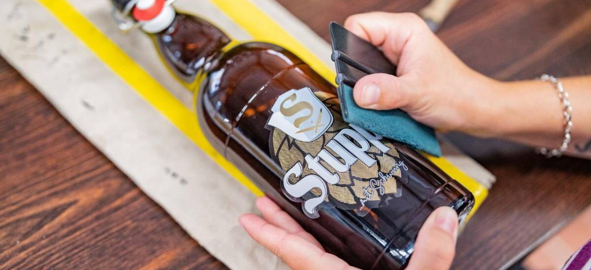 Beklebung einer abgefüllten Flasche Stupps Bier mit Logo